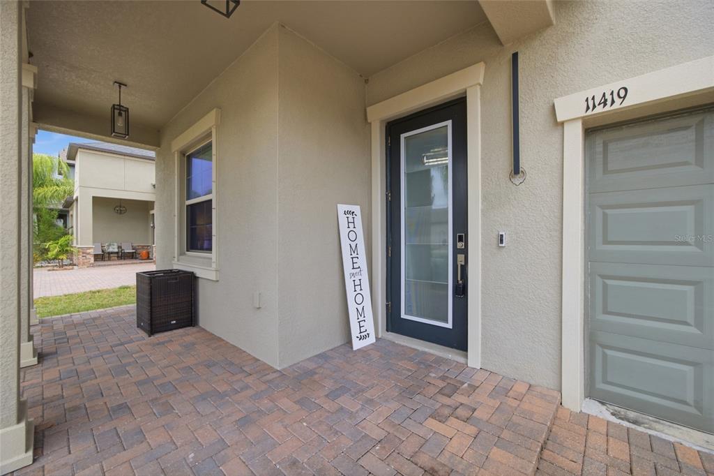 A paved entryway features a dark front door with a vertical sign and a garage — 11419 SUNBURST MARBLE ROAD, RIVERVIEW, FL