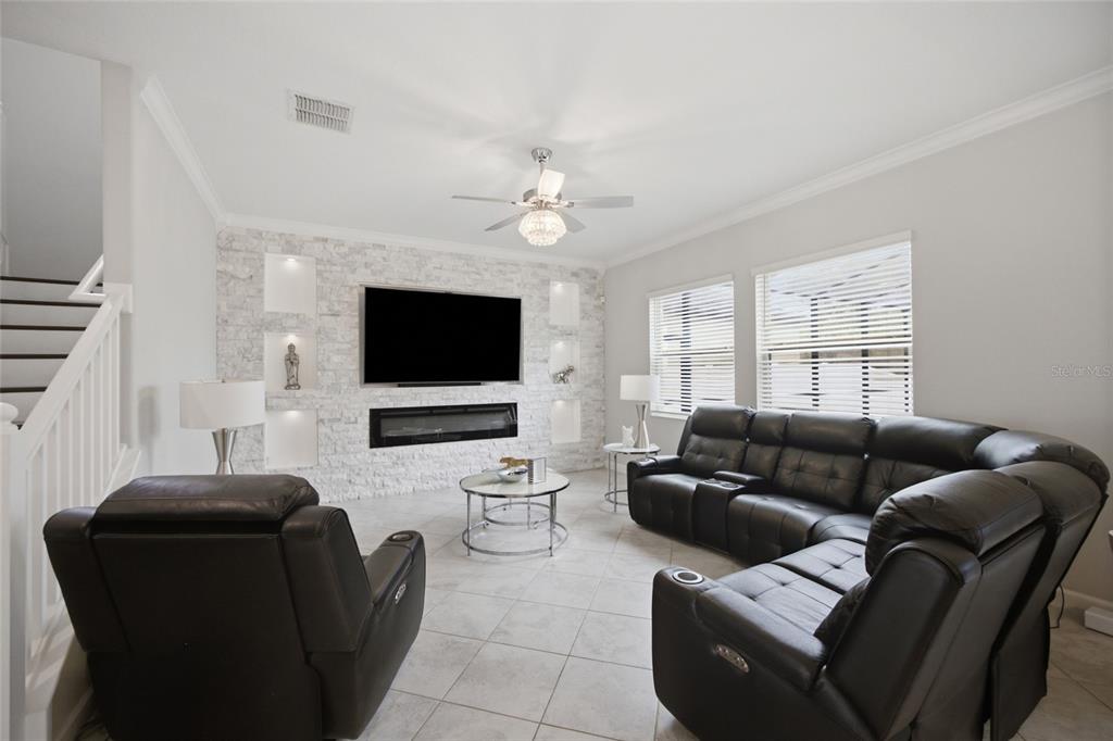 A living room features a white stone fireplace wall, a black sectional, and tile flooring — 11419 SUNBURST MARBLE ROAD, RIVERVIEW, FL