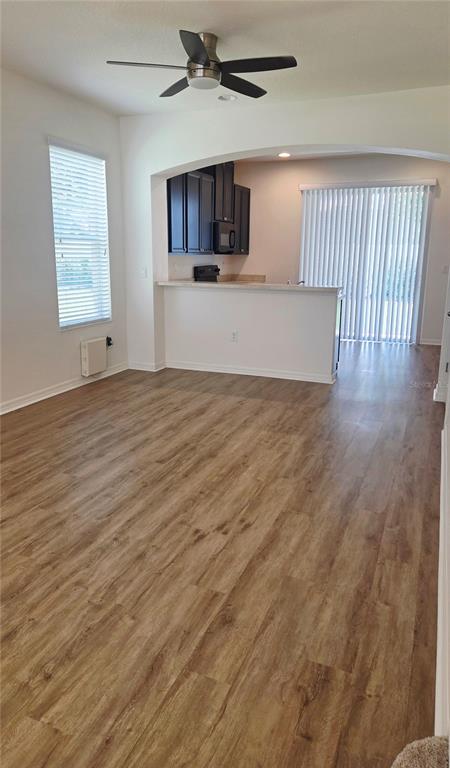 An open-concept living area features wood-look flooring, a ceiling fan, and an adjacent kitchen — 8821 WALNUT GABLE COURT, RIVERVIEW, FL