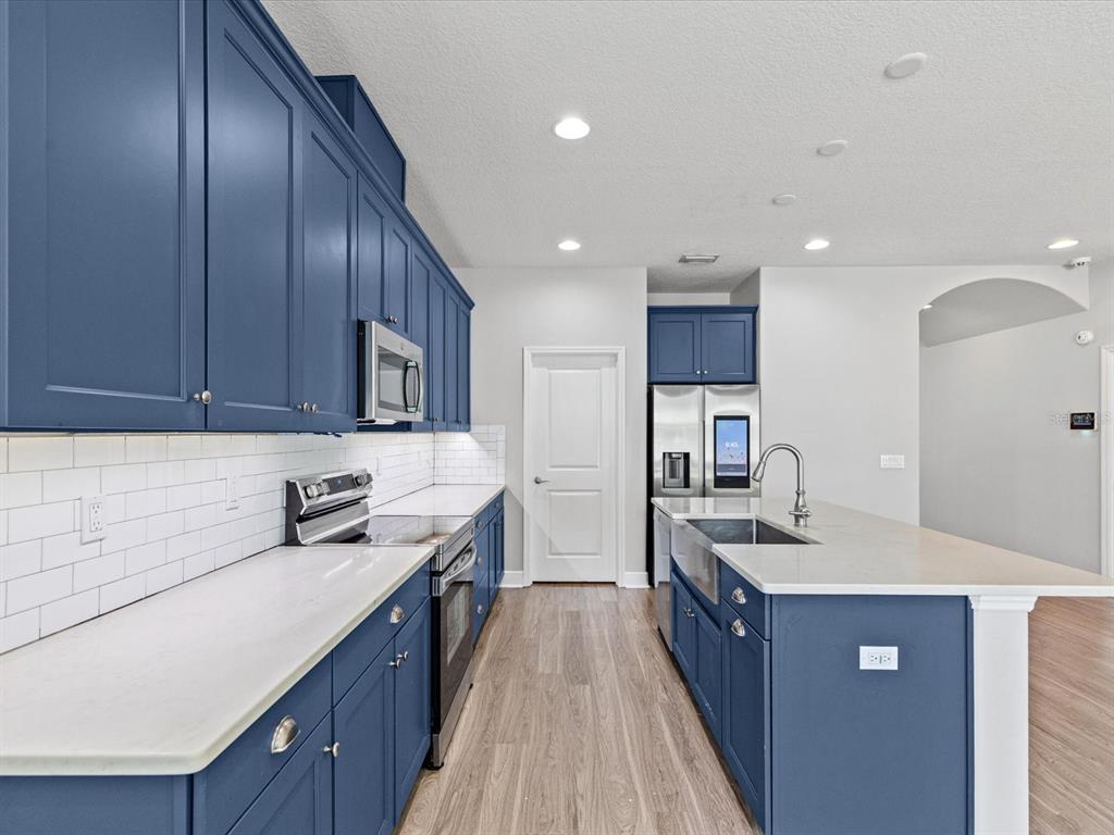 A kitchen features blue cabinets, white countertops, a subway tile backsplash, and a center island — 7105 PARK TREE DRIVE, TAMPA, FL