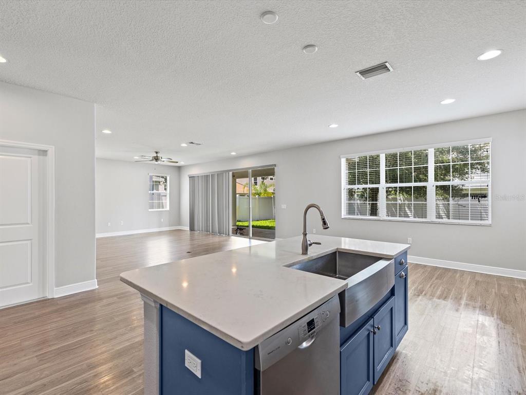 A kitchen island with a farmhouse sink and blue cabinets overlooks an open living area — 7105 PARK TREE DRIVE, TAMPA, FL