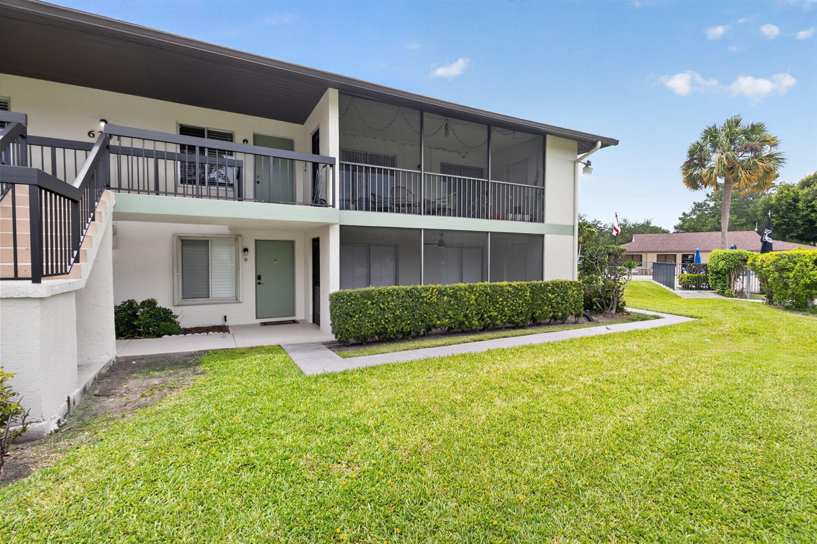 A two-story apartment building features a ground-level patio and an upper-level screened balcony — 6341 Chasewood Drive # D, Jupiter FL 33458, JUPITER, FL