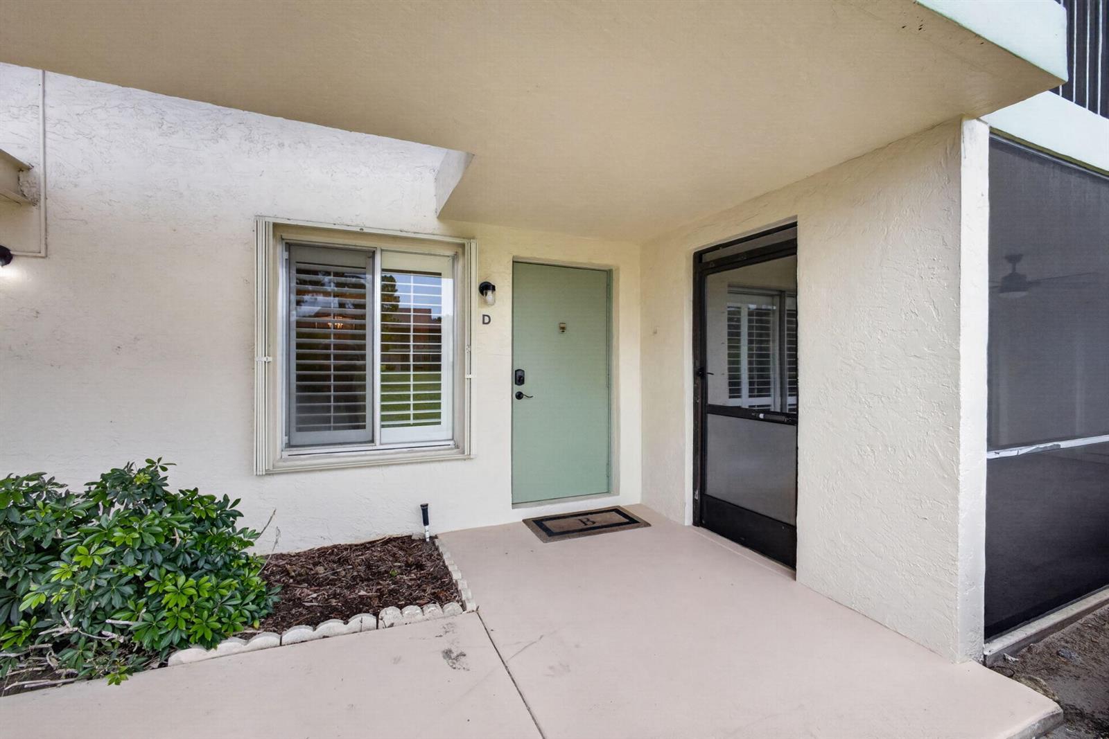 The exterior view shows a light-colored building entrance with a green door and window — 6341 Chasewood Drive # D, Jupiter FL 33458, JUPITER, FL