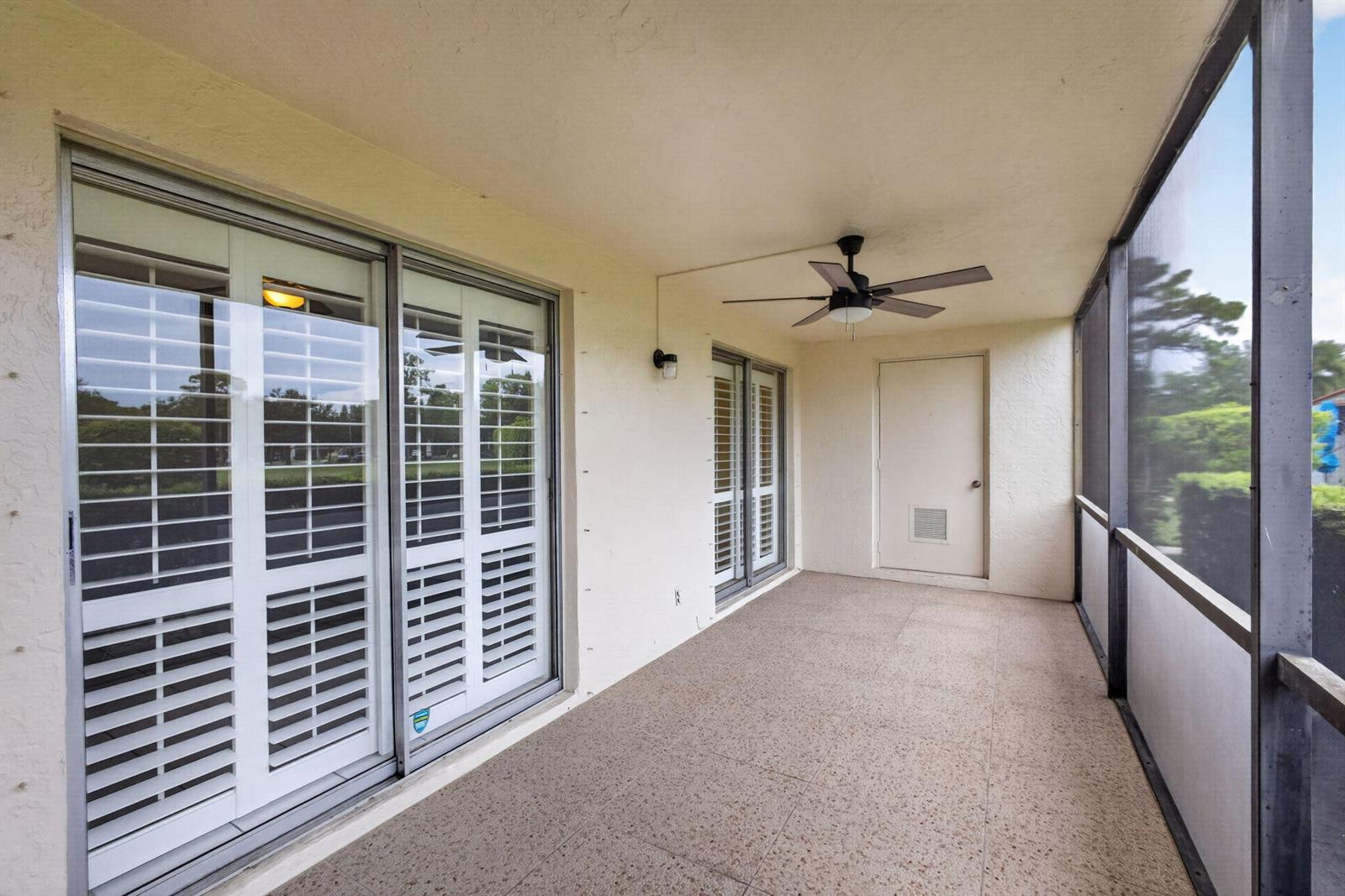 A screened-in patio features tiled flooring, a ceiling fan, and sliding glass doors — 6341 Chasewood Drive # D, Jupiter FL 33458, JUPITER, FL