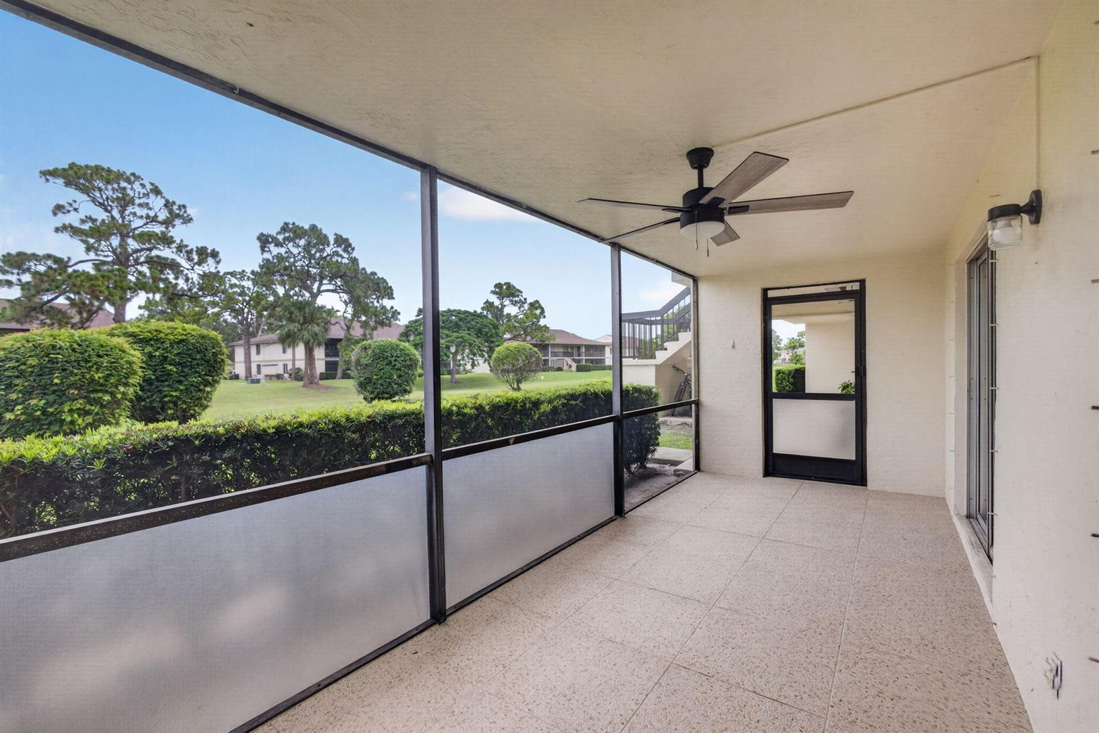 A screened-in patio features a ceiling fan, tiled flooring, and a view of green landscaping — 6341 Chasewood Drive # D, Jupiter FL 33458, JUPITER, FL