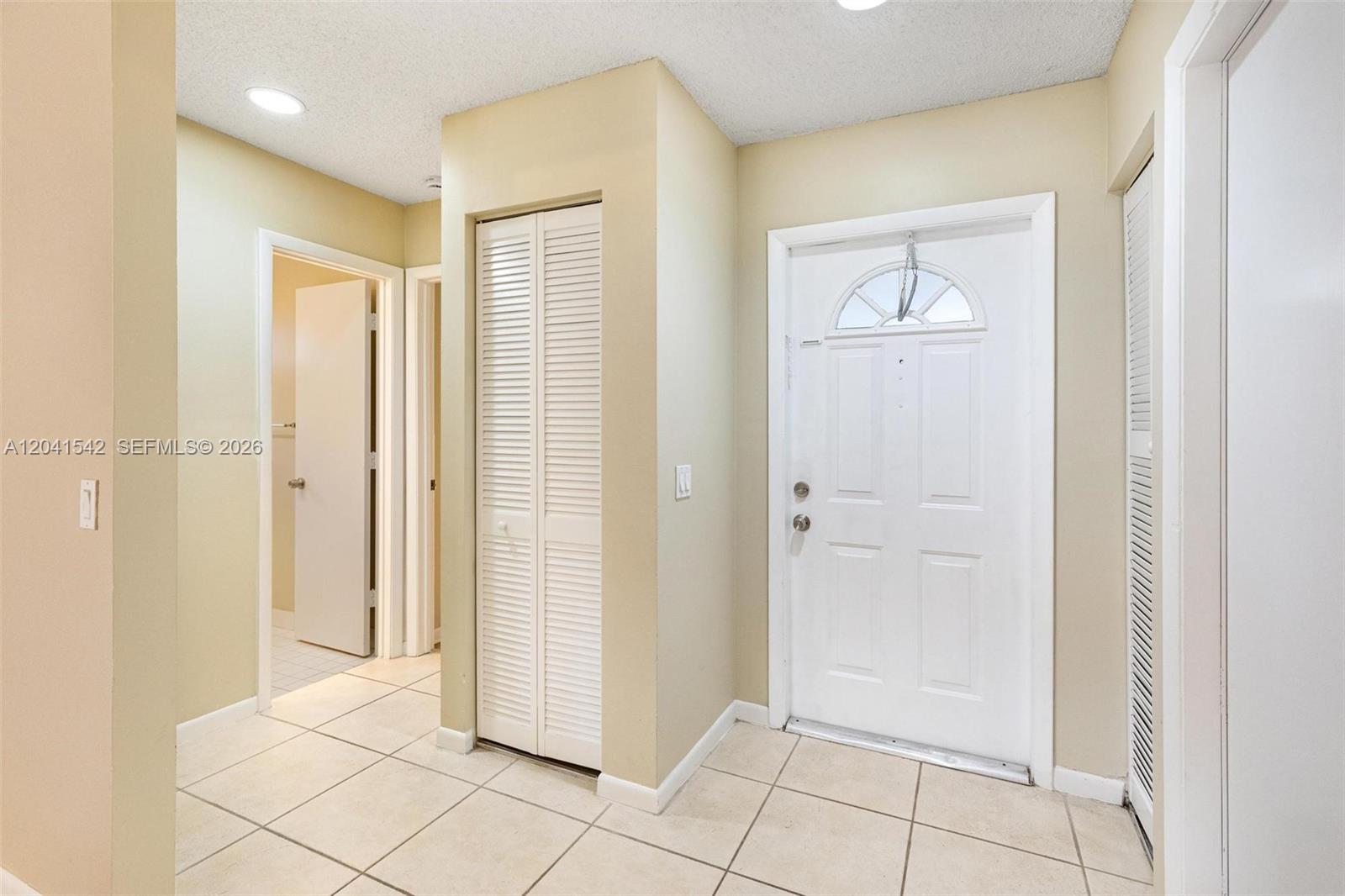 An entryway features a white front door, tiled flooring, and several louvered closet doors — 1513 Garden Rd, Weston FL 33326, WESTON, FL