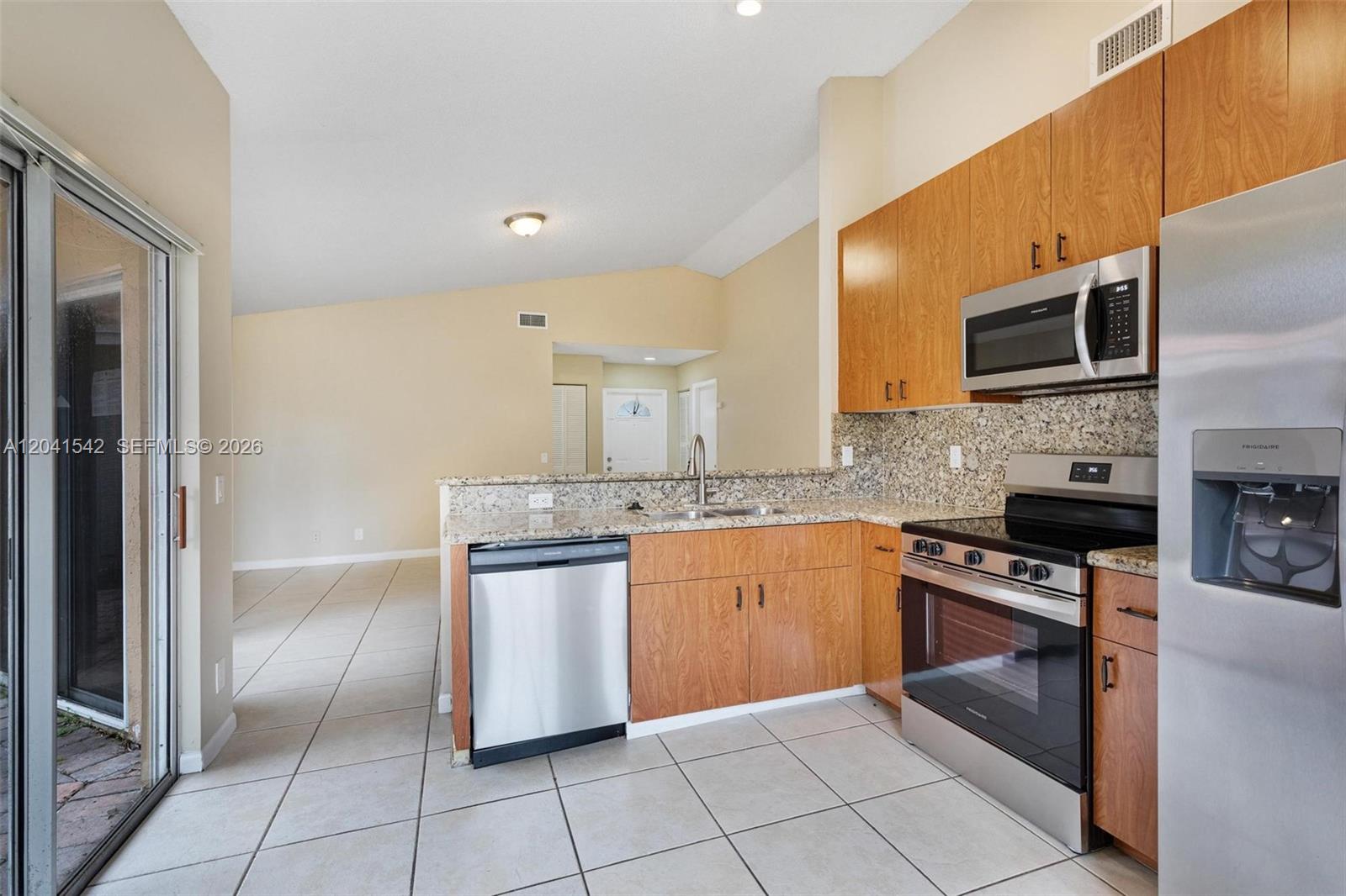 A kitchen features wood cabinets, granite countertops, stainless steel appliances, and tile flooring — 1513 Garden Rd, Weston FL 33326, WESTON, FL