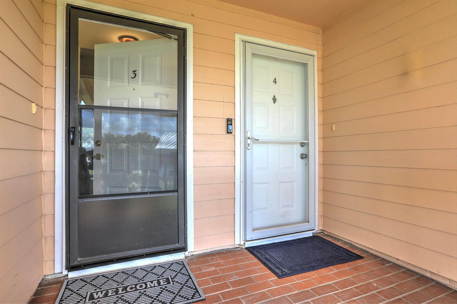Two exterior doors labeled 3 and 4 with storm doors on a brick porch — 5720 Pelican Pointe Drive # 3, Sebastian FL 32958, SEBASTIAN, FL