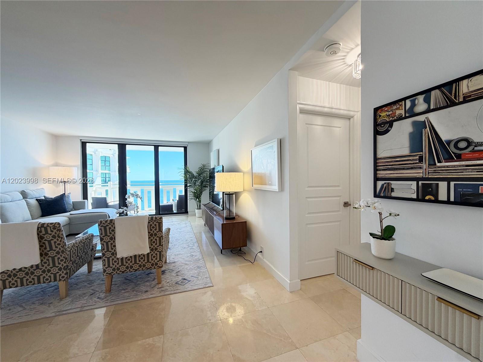 A living room with tile floors, patterned armchairs, and a balcony overlooking the ocean — 1111 Crandon Blvd # B1105, Key Biscayne FL 33149, KEY BISCAYNE, FL