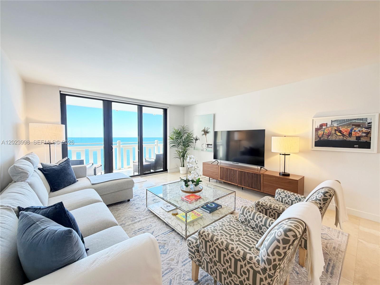 A living room features a sectional sofa, patterned armchairs, and a glass coffee table — 1111 Crandon Blvd # B1105, Key Biscayne FL 33149, KEY BISCAYNE, FL