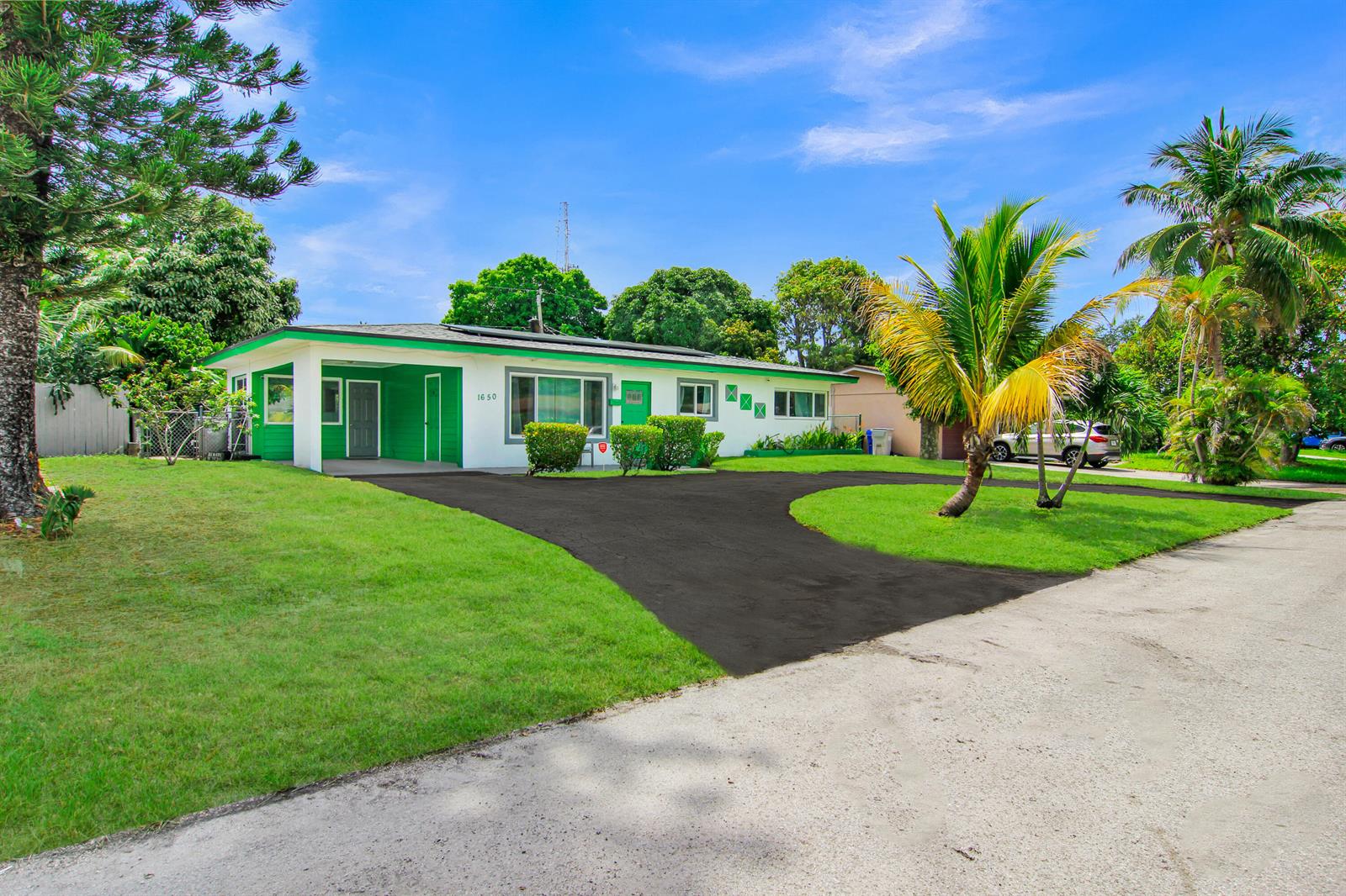 A rectangular swimming pool sits in a backyard with a lawn, trees, and house exterior — 1650 NW 1st Way, Pompano Beach FL 33060, POMPANO BEACH, FL