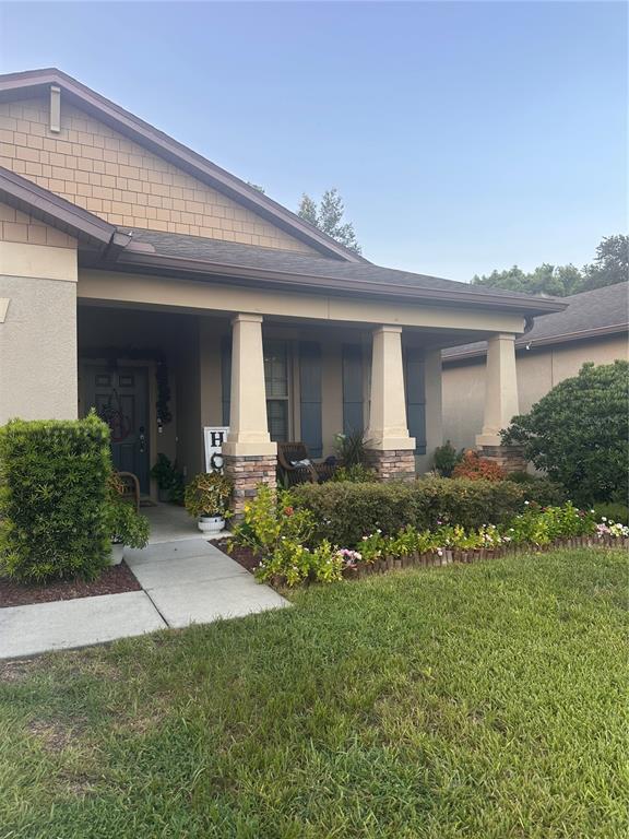 A single-story house features a covered front porch with stone-based columns and landscaping — 15541 STONE HOUSE DRIVE, BROOKSVILLE, FL