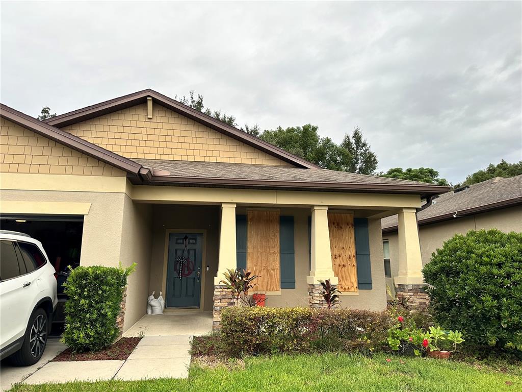 A living room features two gray sofas, a chandelier, tile flooring, and a sliding glass door — 15541 STONE HOUSE DRIVE, BROOKSVILLE, FL