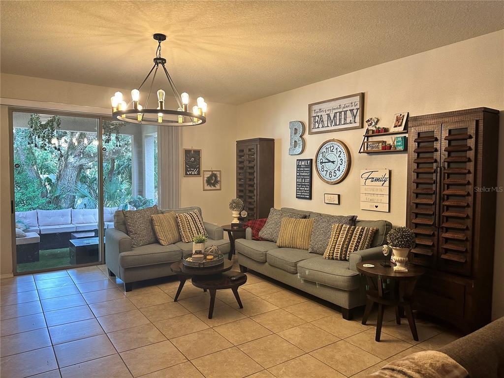 A dining room with a wooden table and chairs sits in front of a living area — 15541 STONE HOUSE DRIVE, BROOKSVILLE, FL