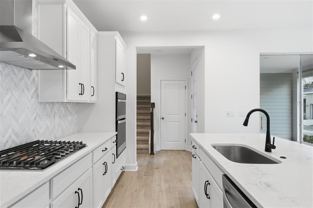 A modern white kitchen features a gas cooktop, double wall ovens, and a center island — 1943 SEAWALL WAY, CELEBRATION, FL