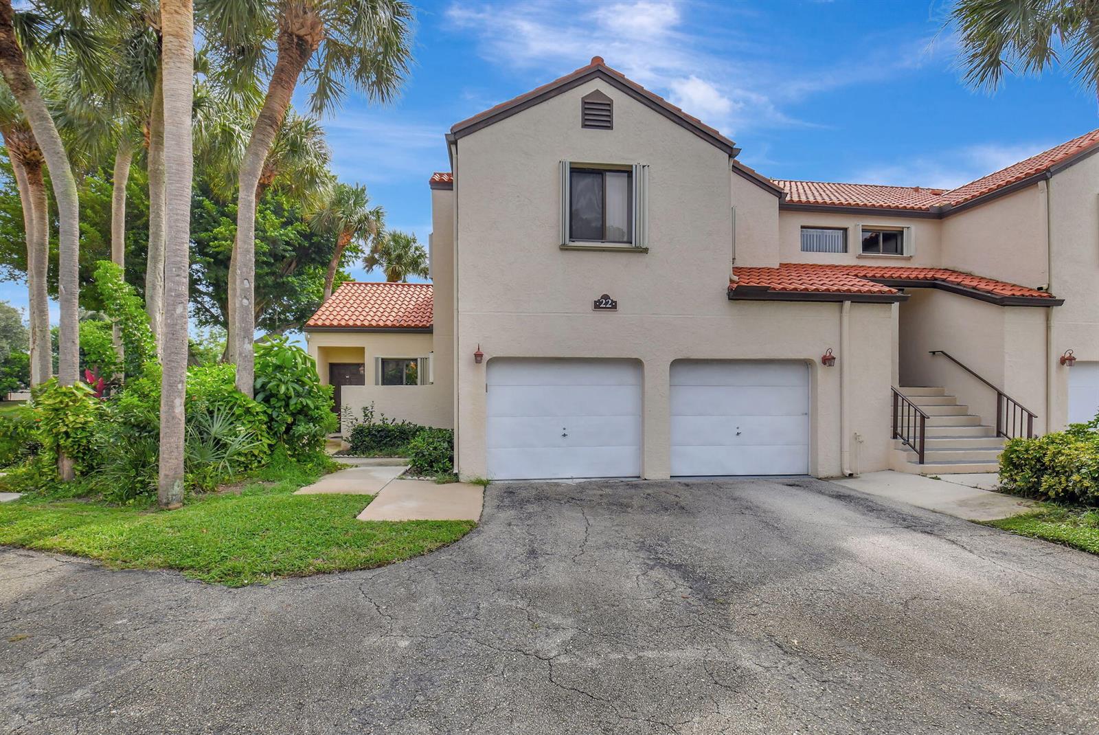 A two-story townhouse with a two-car garage, tile roof, and an exterior staircase — 22 Via De Casas Sur # 101, Boynton Beach FL 33426, BOYNTON BEACH, FL