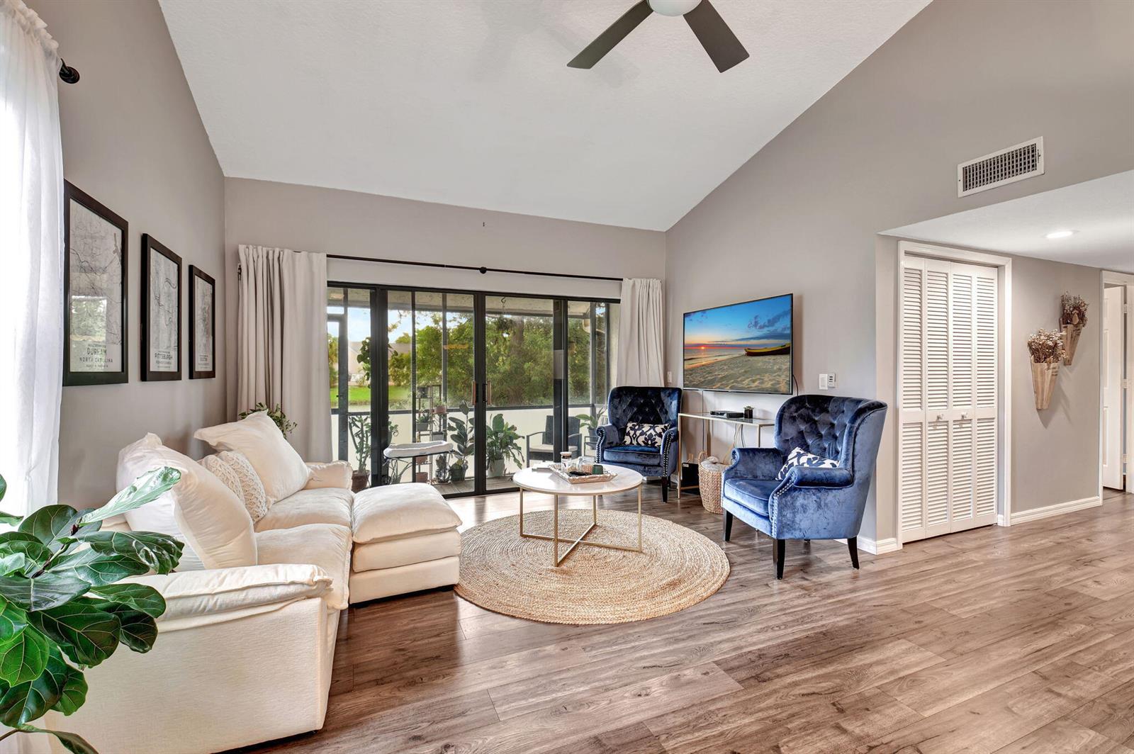 A living room features a white sectional, two blue velvet chairs, and sliding glass doors — 22 Via De Casas Sur # 101, Boynton Beach FL 33426, BOYNTON BEACH, FL