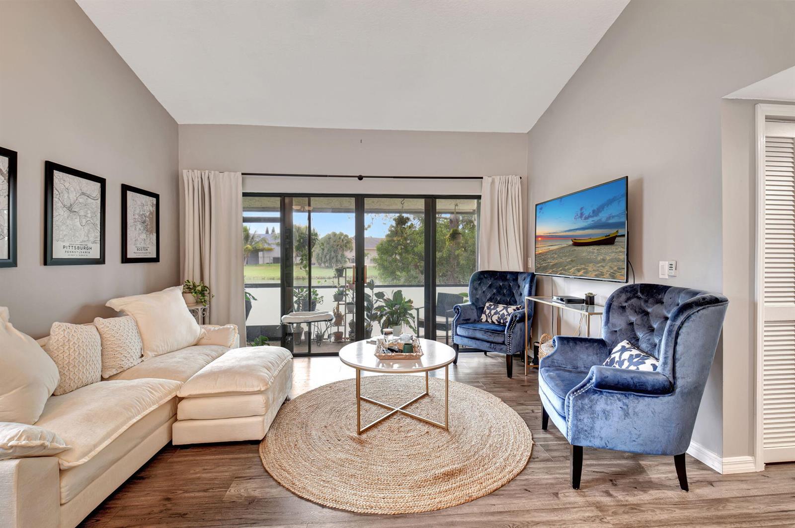 A living room features a white sectional, two blue velvet armchairs, and a sliding glass door — 22 Via De Casas Sur # 101, Boynton Beach FL 33426, BOYNTON BEACH, FL
