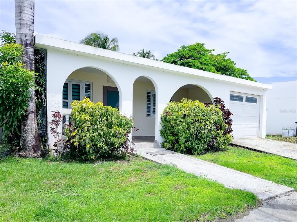 A white, single-story house features three arched openings, a garage, and large green bushes — Coco Beach S 110 GAVIOTA UNIT 110, RIO GRANDE, PR