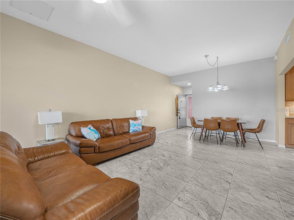 A living and dining area features brown leather sofas, tile flooring, and a dining set — 1102 ASHTON PALMS DRIVE, LAKE WALES, FL