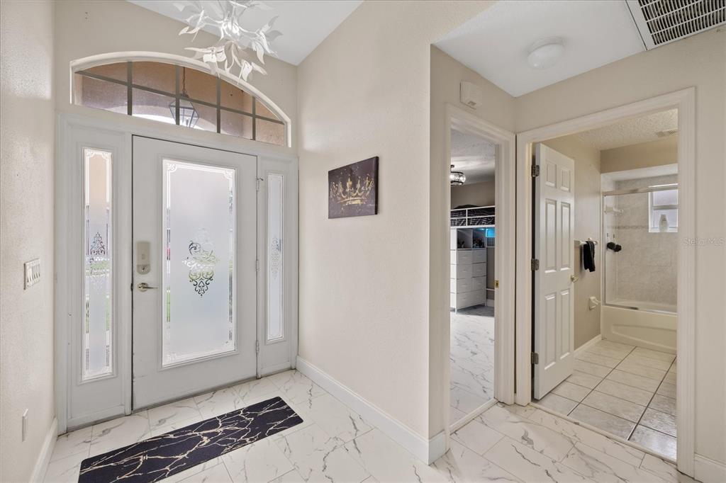 An entryway features a white front door, marble-look tile flooring, and access to a bathroom — 11424 DORIAN COURT, NEW PORT RICHEY, FL
