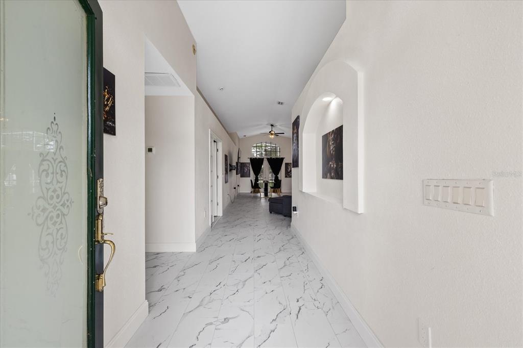 A bright entryway features white marble-look tile flooring and an arched wall niche — 11424 DORIAN COURT, NEW PORT RICHEY, FL