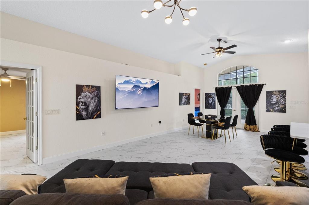 A spacious living room features white marble floors, a wall-mounted television, and black lion-themed decor — 11424 DORIAN COURT, NEW PORT RICHEY, FL