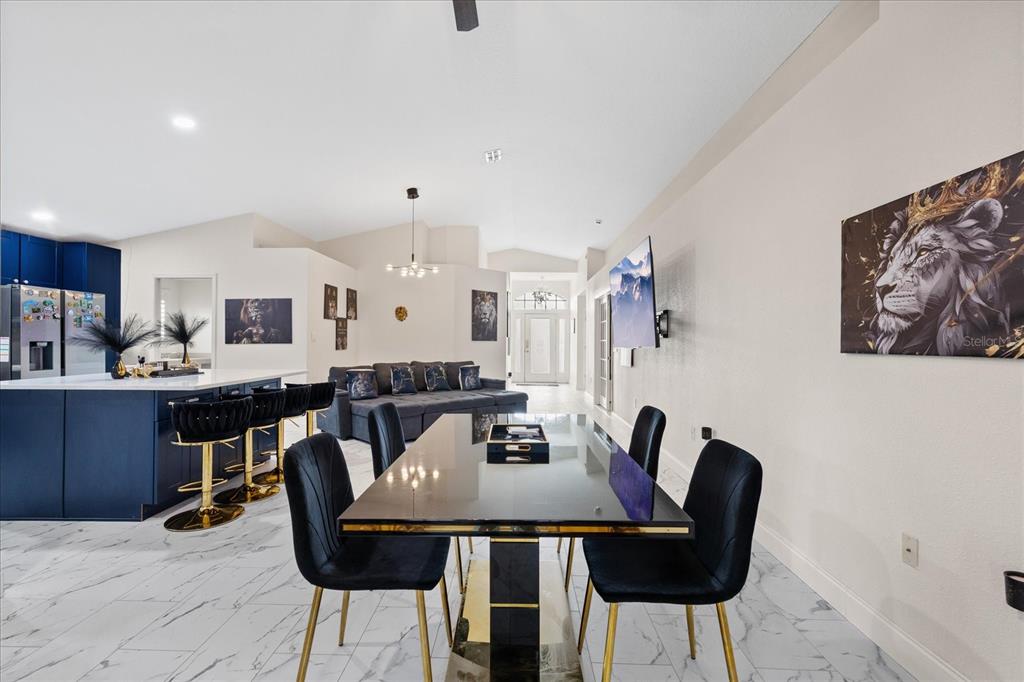 A dining area with a black table and chairs sits in front of a kitchen — 11424 DORIAN COURT, NEW PORT RICHEY, FL