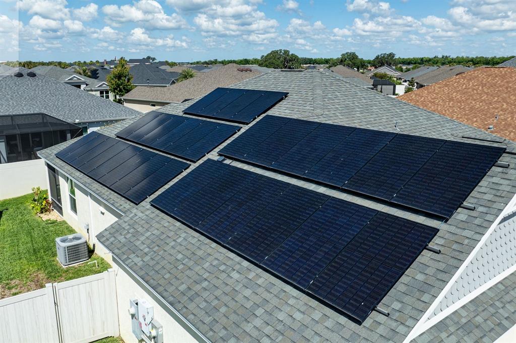 An aerial view shows solar panels installed on the shingled roof of a residential home — 580 GOUGH PLACE, THE VILLAGES, FL