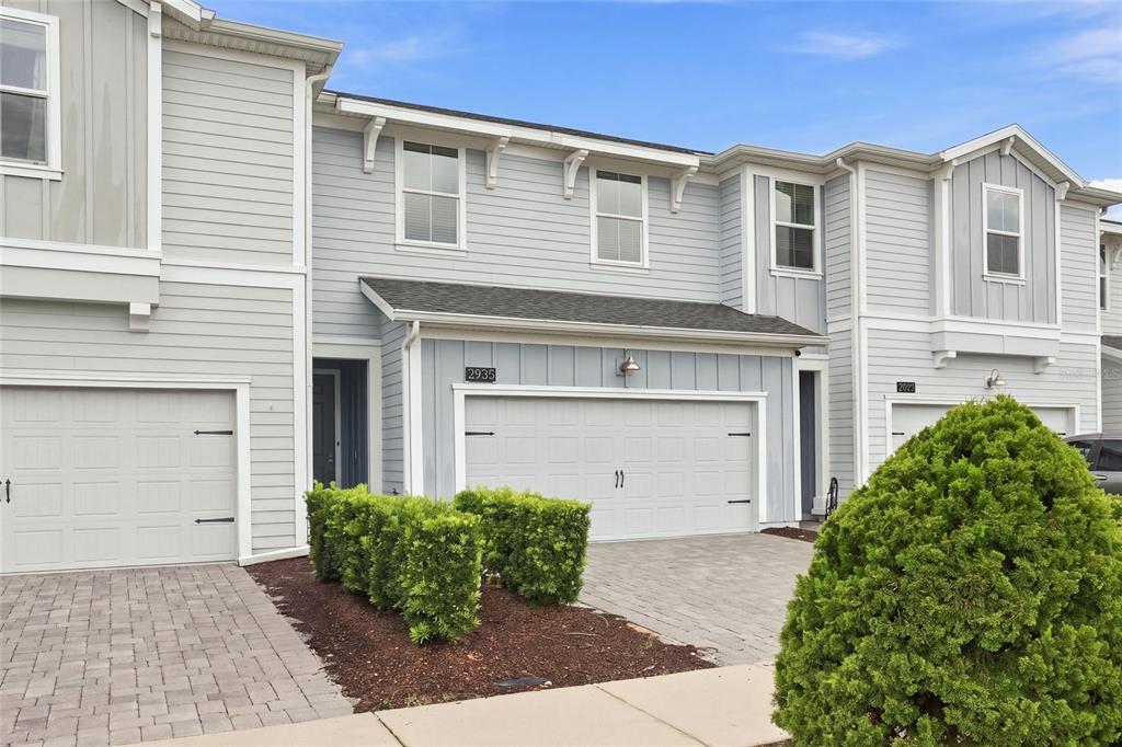 A two-story townhouse exterior with light blue siding, a two-car garage, and a paved driveway — 2935 THEME STREET, KISSIMMEE, FL