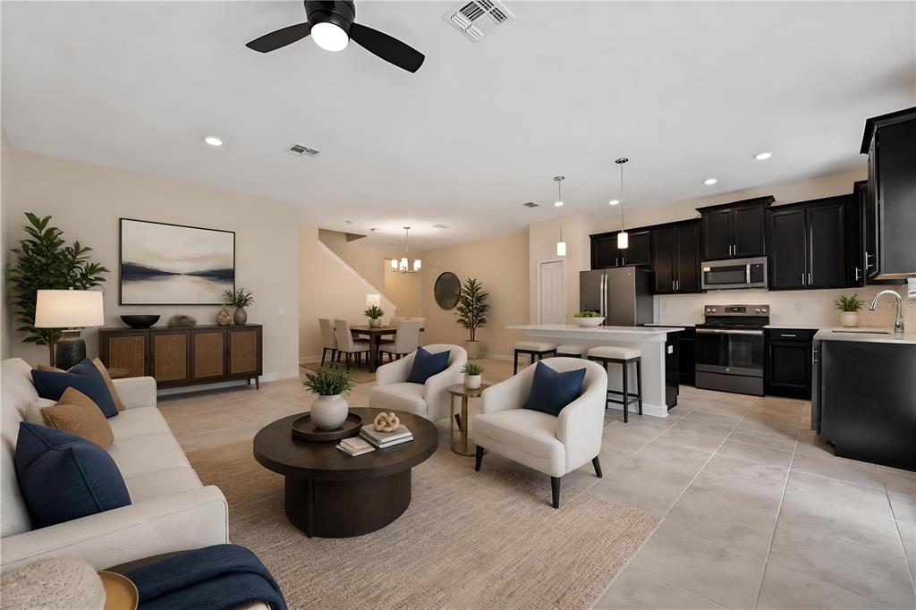 An open-concept living room and kitchen featuring dark cabinetry, neutral furniture, and tile flooring — 2935 THEME STREET, KISSIMMEE, FL