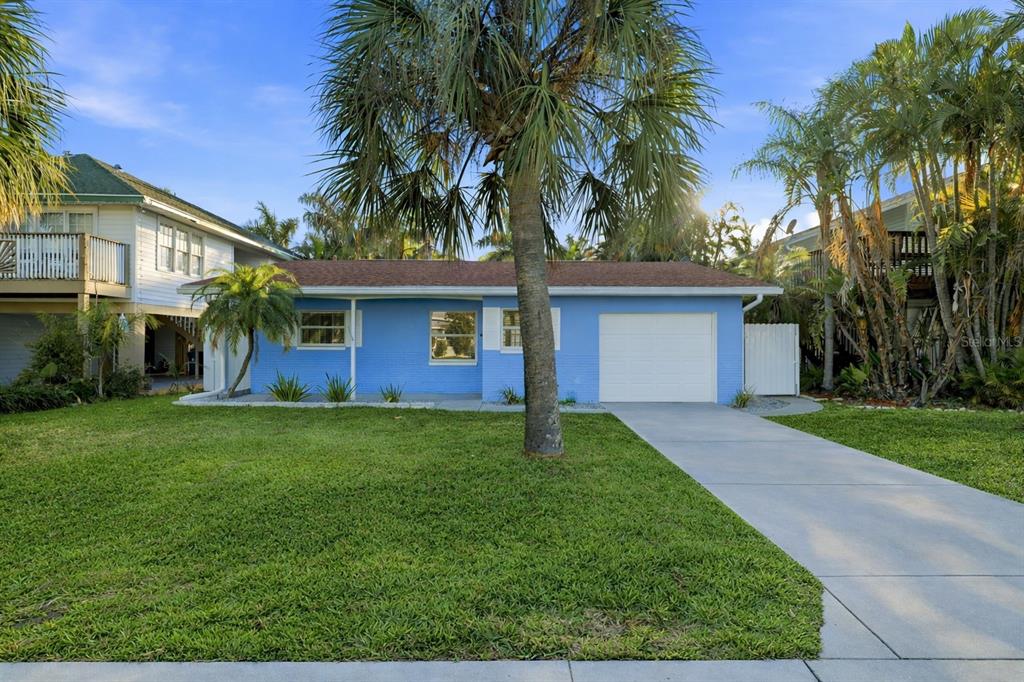 A single-story blue house with a white garage door and a palm tree in front — 17734 1ST STREET E, REDINGTON SHORES, FL