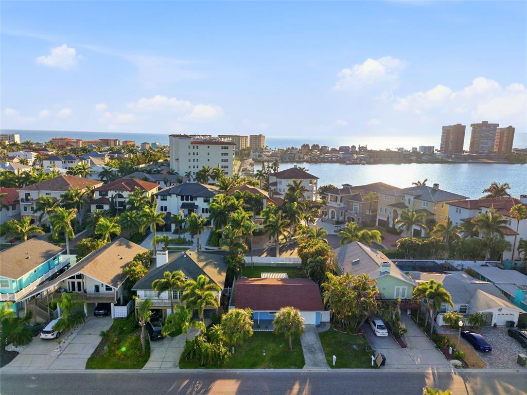 An aerial view of a coastal neighborhood featuring houses, palm trees, and a nearby bay — 17734 1ST STREET E, REDINGTON SHORES, FL