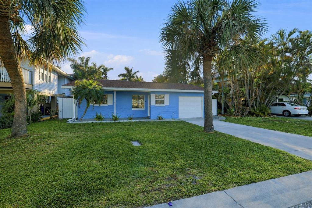 A single-story blue house with a white garage door and palm trees in the front yard — 17734 1ST STREET E, REDINGTON SHORES, FL