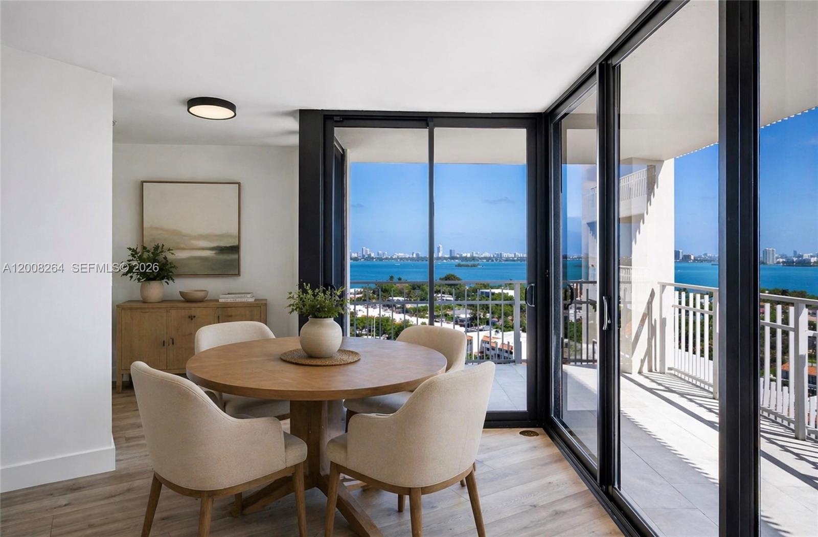 A dining area with a round wooden table and balcony access overlooking the bay — 2000 Towerside Ter # 1506, Miami FL 33138, MIAMI, FL