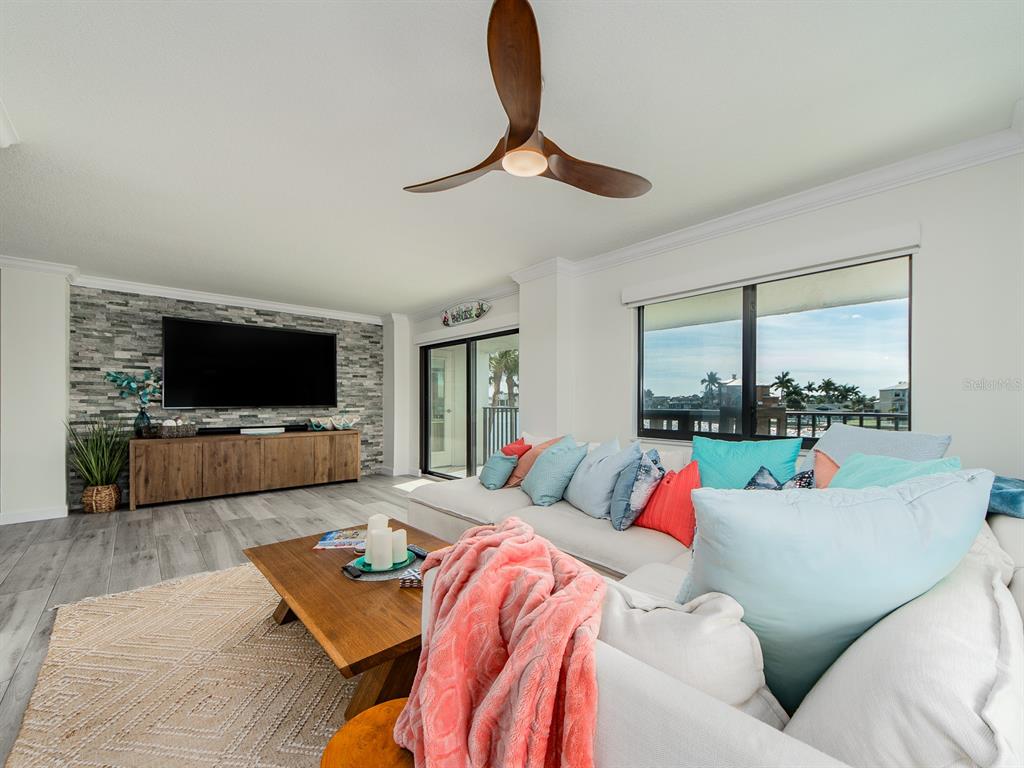 A living room features a stone accent wall, a large sectional sofa, and a ceiling fan — 240 SAND KEY ESTATES DRIVE UNIT 216, CLEARWATER BEACH, FL