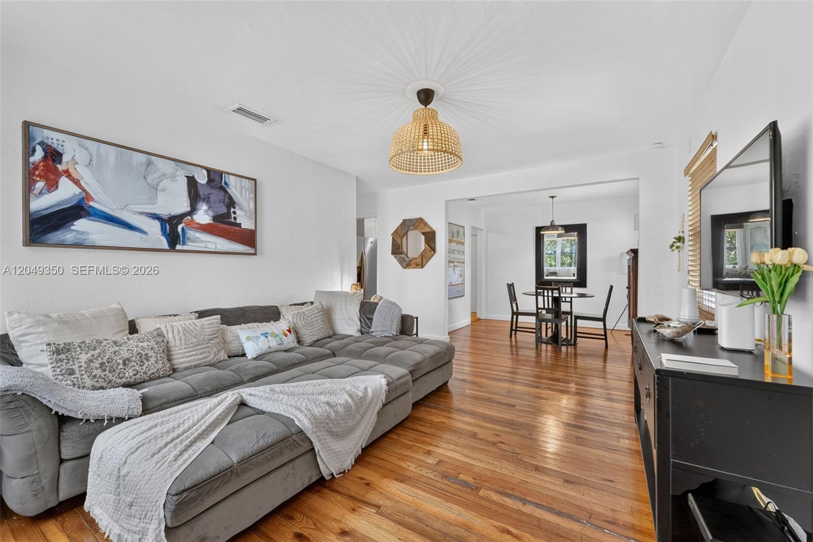 A living room with a grey sectional sofa, hardwood floors, and an adjacent dining area — 5800 SW 61st St, Miami FL 33143, MIAMI, FL
