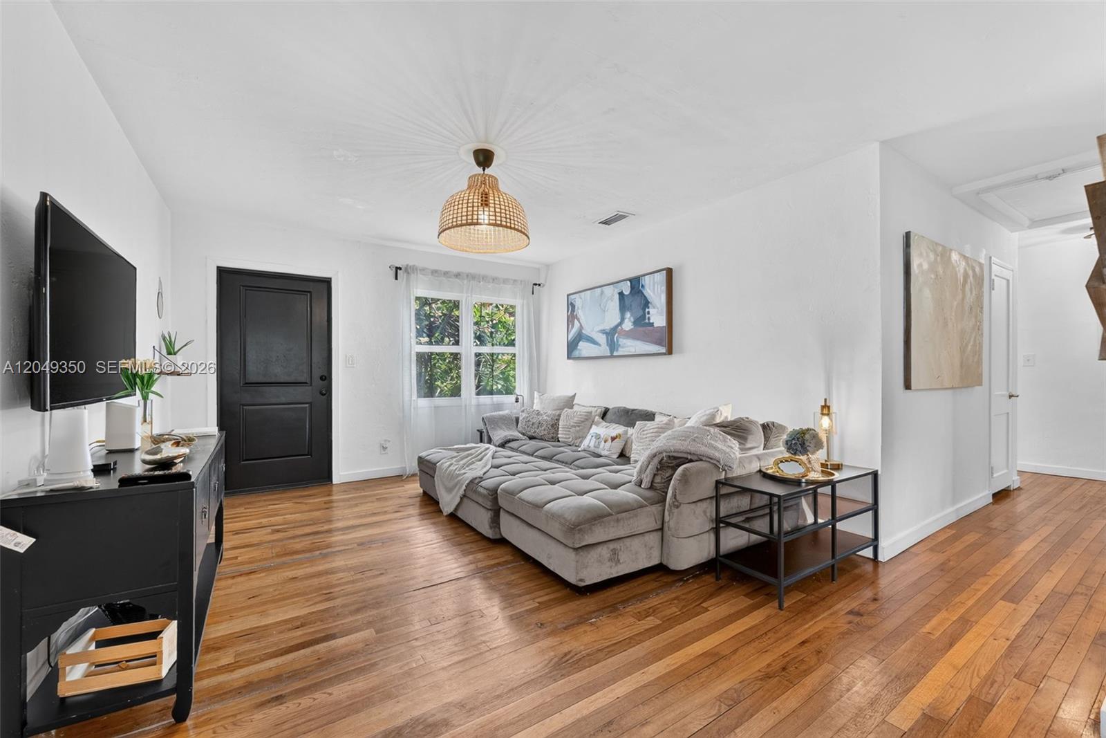 A living room features a grey sectional sofa, hardwood floors, and a black front door — 5800 SW 61st St, Miami FL 33143, MIAMI, FL