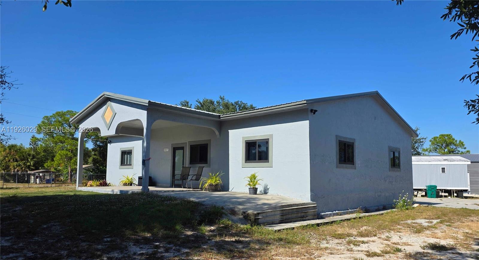 A single-story light gray house with a covered front porch and a metal roof — 527 PERIMETER RD, Clewiston FL 33440, CLEWISTON, FL