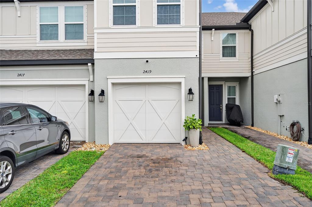 A two-story townhouse exterior features a white garage door, a paved driveway, and a dark-colored front door — 2419 FOGGY CREEK CIRCLE, CLEARWATER, FL