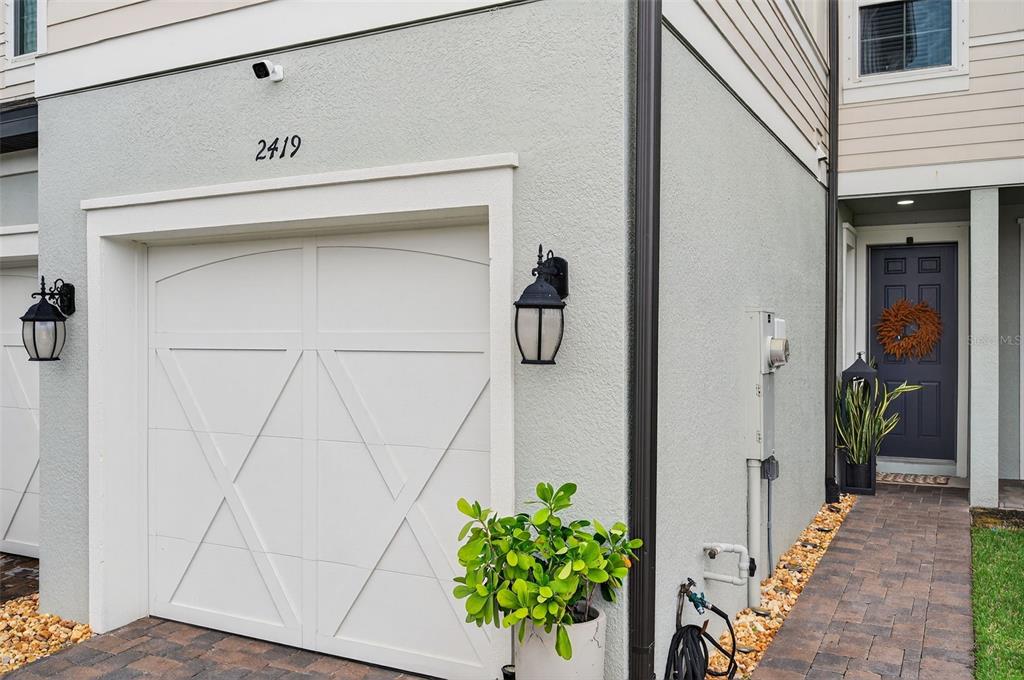 A view of a garage door, a front entrance, and a small potted plant — 2419 FOGGY CREEK CIRCLE, CLEARWATER, FL