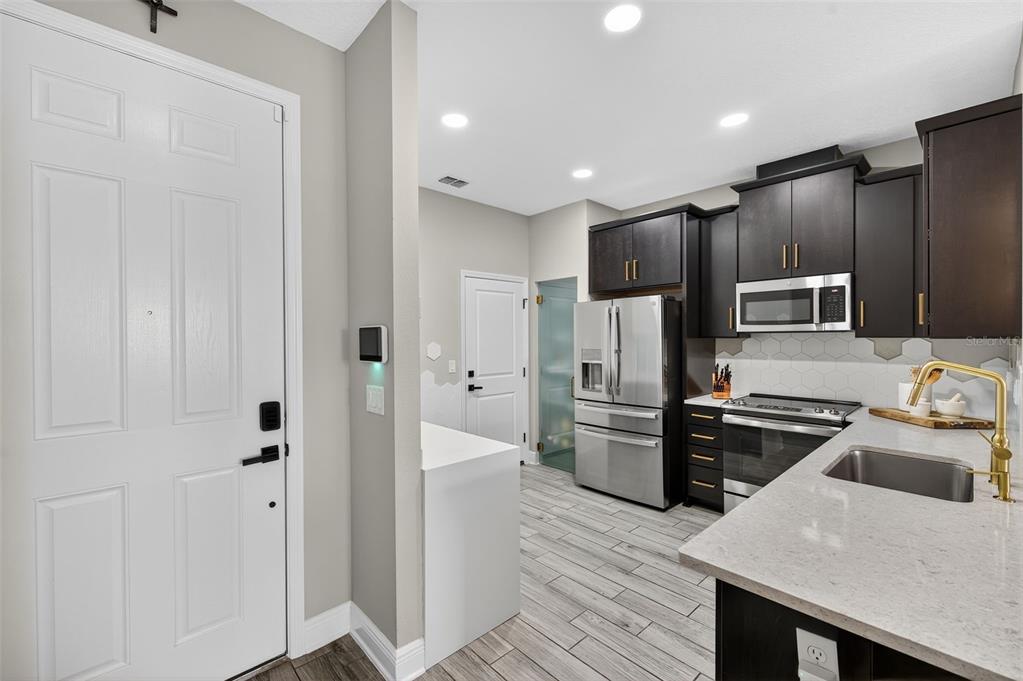 A kitchen with dark cabinets, stainless steel appliances, and a white countertop island — 2419 FOGGY CREEK CIRCLE, CLEARWATER, FL