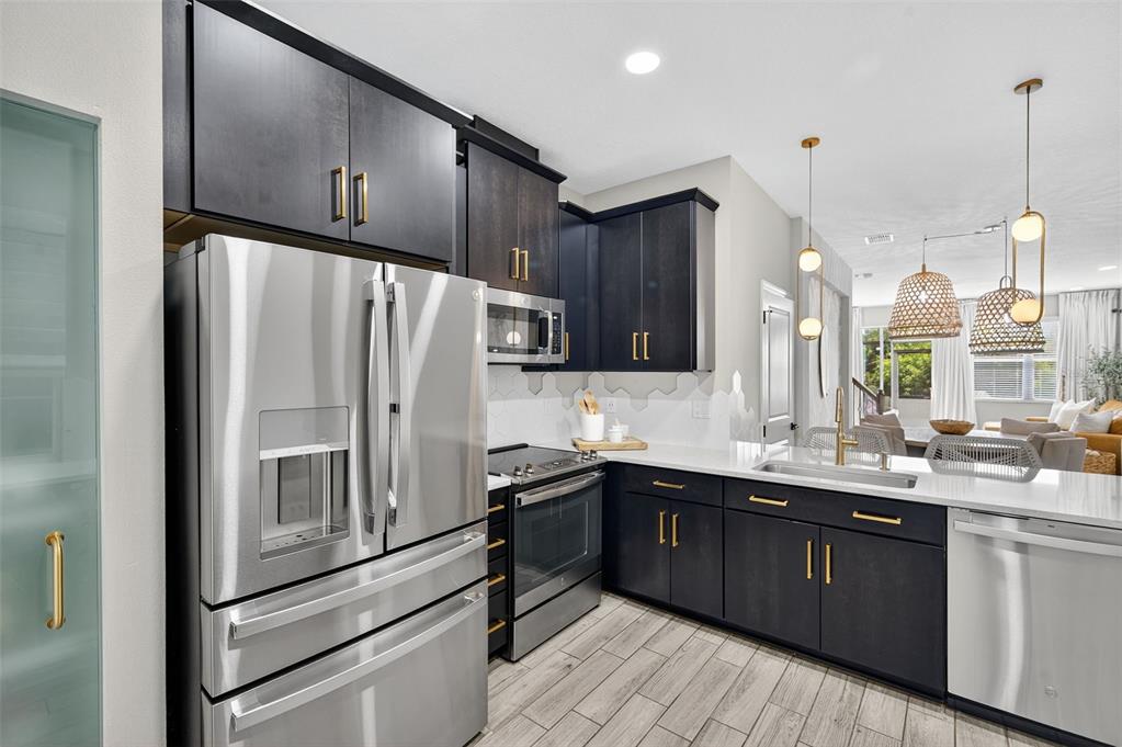 A modern kitchen features dark wood cabinets, stainless steel appliances, and light-colored countertops — 2419 FOGGY CREEK CIRCLE, CLEARWATER, FL