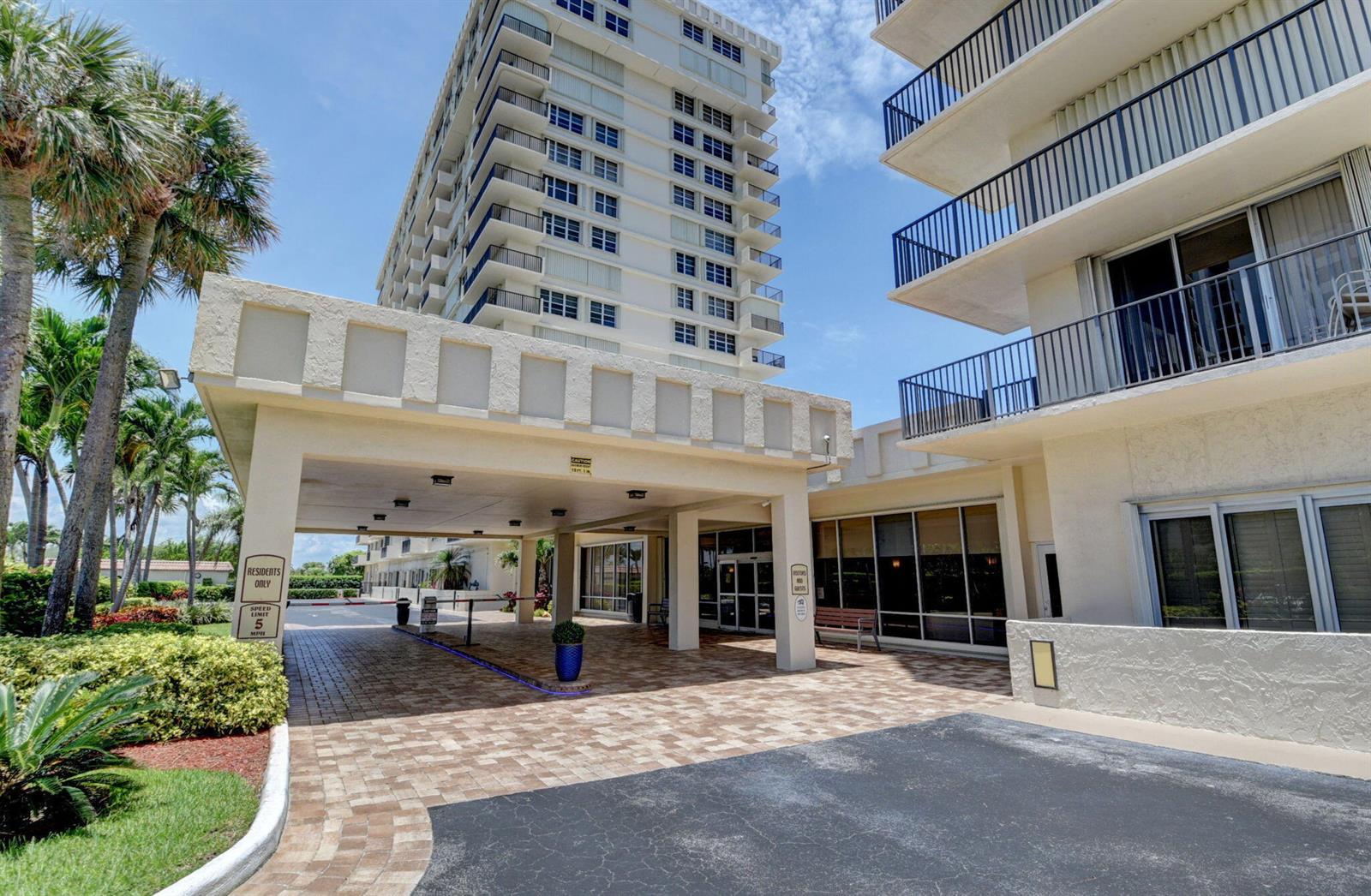 An exterior view of a multi-story apartment building with a covered entrance and paved driveway — 2121 N Ocean Boulevard # 1406w, Boca Raton FL 33431, BOCA RATON, FL
