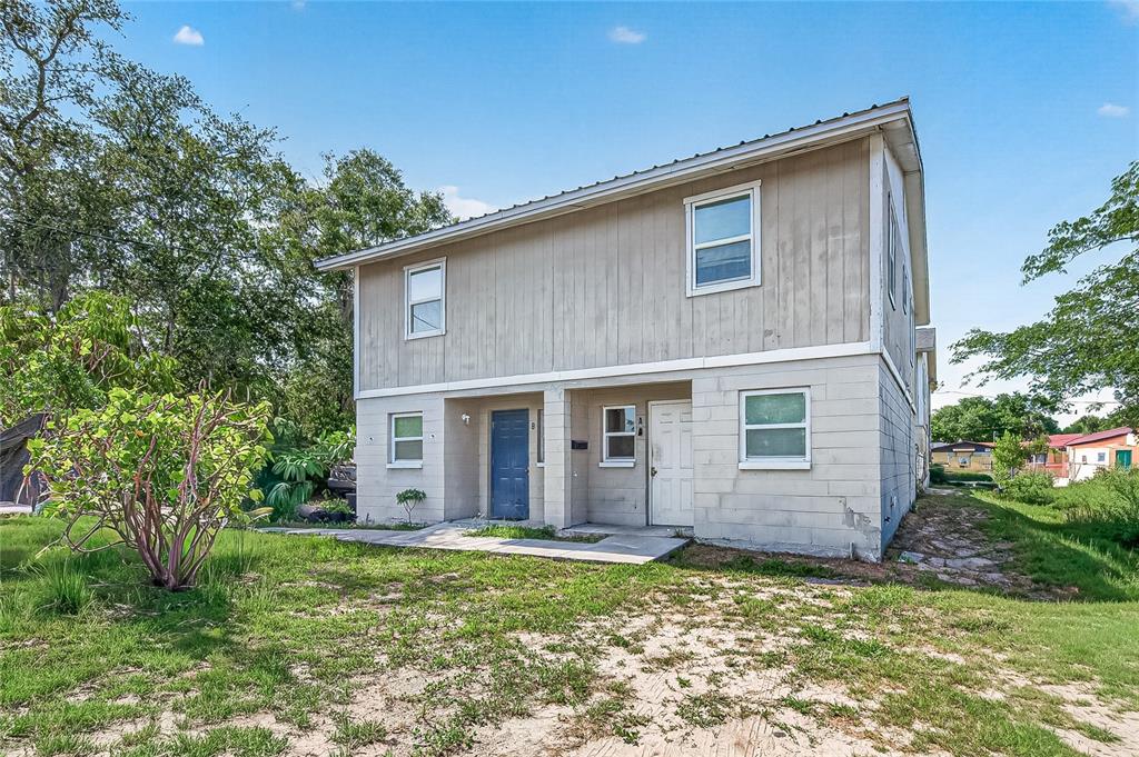 A two-story duplex with light-colored siding and concrete block walls under a metal roof — 3602 N 54TH STREET, TAMPA, FL