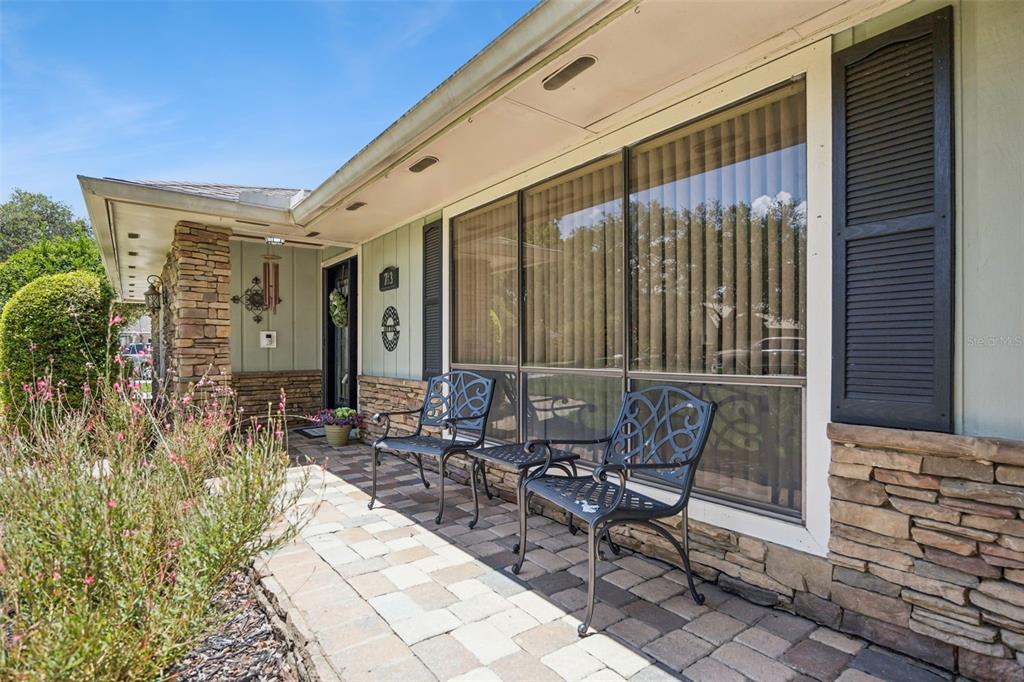 A stone-accented front porch features two metal chairs and a large window with shutters — 783 KEENELAND PIKE, LAKE MARY, FL