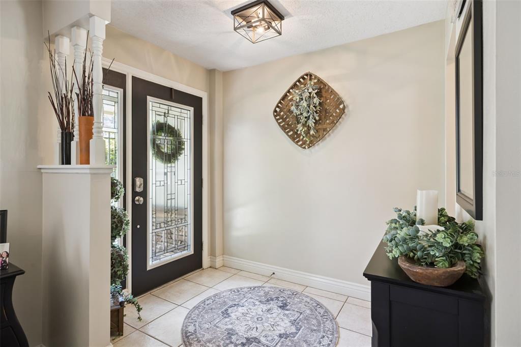 A bright entryway features tile flooring, a dark front door, and a decorative wall basket — 783 KEENELAND PIKE, LAKE MARY, FL