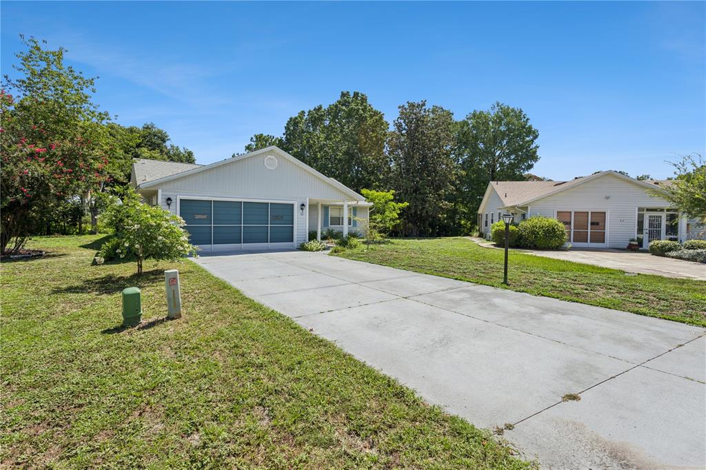 A single-story house with a concrete driveway and a blue garage door sits outdoors — 32 GORDON COURT, LEESBURG, FL