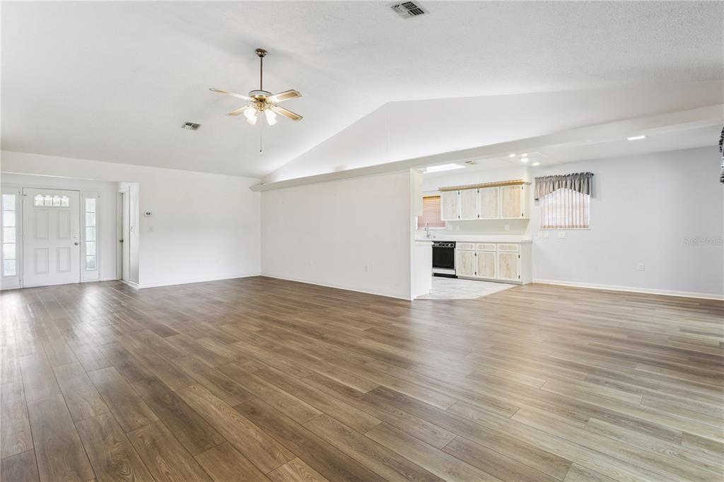 A sunroom with gray carpeting and large windows overlooking a grassy yard and trees — 32 GORDON COURT, LEESBURG, FL