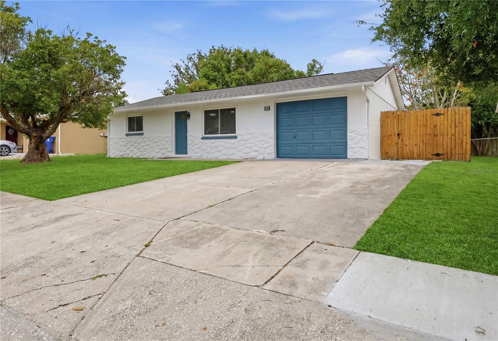 A single-story white house with a blue garage door and a concrete driveway — 6338 ABERDEEN AVENUE, NEW PORT RICHEY, FL